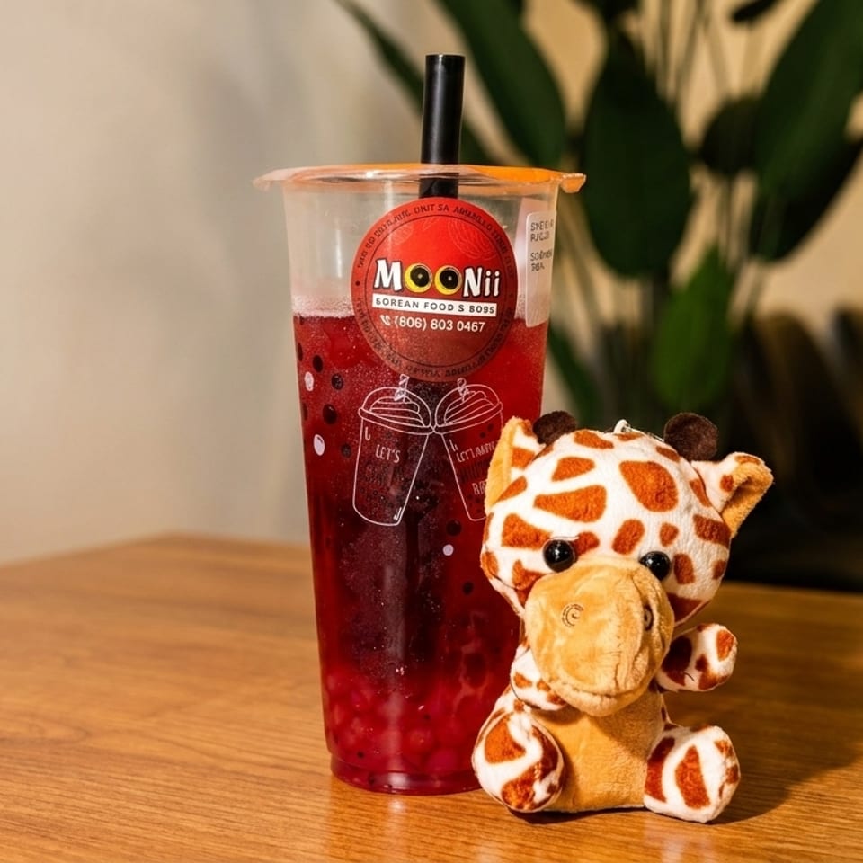 A Moonii Korean Food & Boba drink with a giraffe plushie on a wooden table.